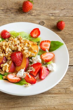 Ev yapımı granola, beyaz peynir ve sağlıklı vegan diyet vejetaryen organik kahvaltı, yemek, yemek, salata için beyaz tabakta bal ile taze meyve salatası