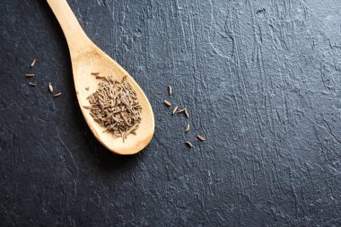 Kimyon tohumu. (Zira) kimyon rustik tahta kaşık ve siyah arka plan görüntüsünü kapatmak.