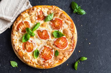 Pizza Margherita siyah taş zemin üzerine. Pizza Margarita domates, fesleğen ve Mozzarella peyniri ile kopya alanı ile.
