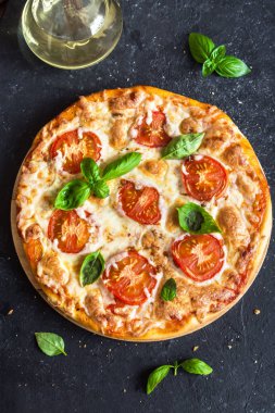 Pizza Margherita siyah taş zemin üzerine. Pizza Margarita domates, fesleğen ve Mozzarella peyniri ile kopya alanı ile.