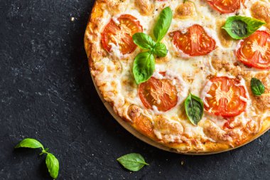 Siyah taş arka planda pizza margherita. Domates, fesleğen ve Mozzarella peynirli pizza..