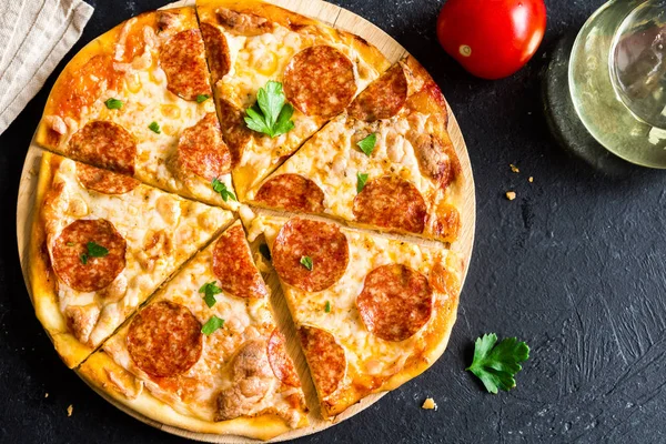 Pepperoni Pizza - Fresh homemade pizza with pepperoni, cheese and tomato sauce on rustic black stone background with copy space.