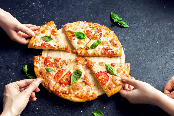 People Hands Taking Slices Of Pizza Margherita. Pizza Margarita and  Hands close up over black background.