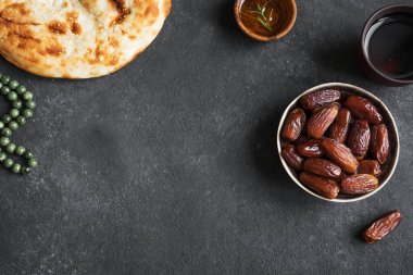 Geleneksel Ramazan, iftar yemeği - hurma meyveleri, ramazan taze ekmek, zeytinyağı, siyah üzerine su ve tespih, üst manzara, kopyalama alanı. Ramazan Kareem kavramı.