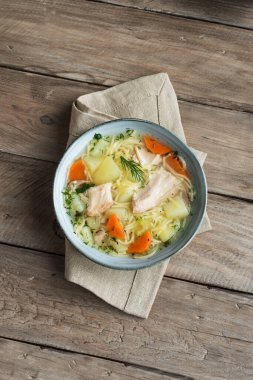 Erişteli tavuk çorbası ve kırsal ahşap arka planda sebzeler, üst manzara, fotokopi alanı. Ev yapımı sağlıklı yemek, taze tavuk ya da hindi çorbası..