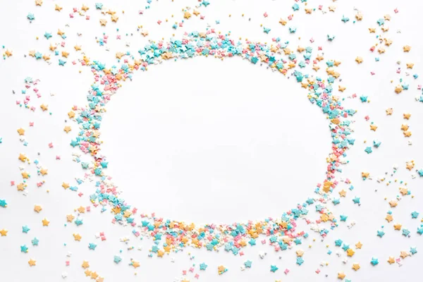 Colorful Sugar Sprinkles on white background, top view, round copy space. Sweet cake pastry ingredient, holiday birthday concept, creative layout.