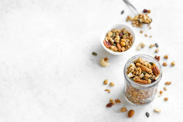 ガラス瓶にナッツと種を入れた自家製グラノーラ 白で健康的な朝食のためのグラノーラ コピースペース — ストック写真