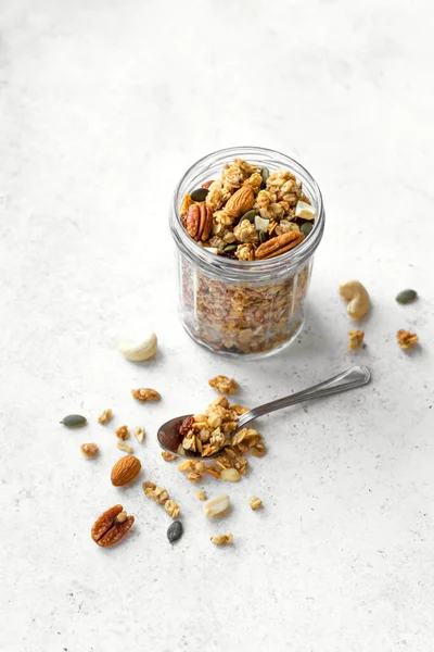 ガラス瓶にナッツと種を入れた自家製グラノーラ 白で健康的な朝食のためのグラノーラ コピースペース — ストック写真