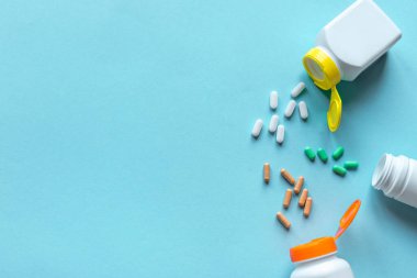 İlaç şişeleri ve mavi arka planda çeşitli haplar, üst manzara, kopyalama alanı. İlaç ve eczane konsepti. Vitaminler veya genel haplar.
