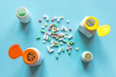 Mavi arka planda çeşitli renkli haplar ve kapsüller, üst manzara, kopyalama alanı. Tıbbi konsept. Çeşitli jenerikler ve vitaminler.