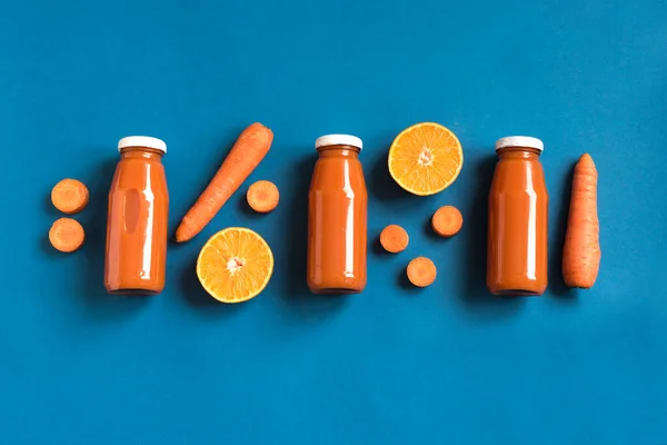 Φρέσκο Καρότο Χυμό Πορτοκάλι Smoothie Μπουκάλια Επίπεδη Θέσει Μπλε Φόντο — Φωτογραφία Αρχείου