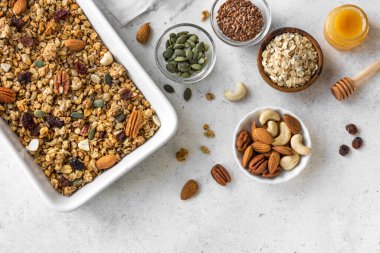 Ceviz, kuru üzüm, bal ve tohumla birlikte kızartılmış Granola. Beyaz üzerine sağlıklı kahvaltı için ev yapımı granola..