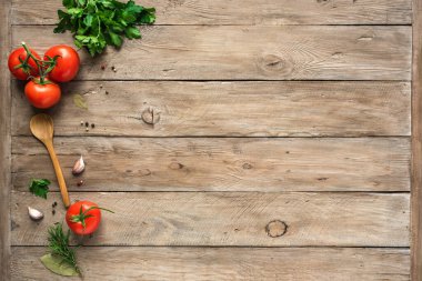 Pişirme geçmişi, ev yemeği konsepti. Olgun domatesler, kaşık, otlar ve baharatlar ahşap arka planda, üst manzara, kopyalama alanı.