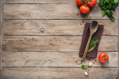 Pişirme geçmişi, ev yemeği konsepti. Olgun domatesler, kaşık, otlar ve baharatlar ahşap arka planda, üst manzara, kopyalama alanı.