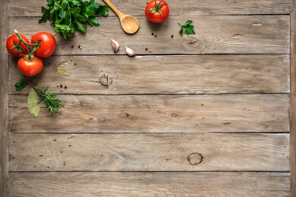 Cooking background, home cooking concept. Ripe tomatoes, spoon, herbs and spices on wooden background, top view, copy space.