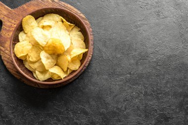 Ev yapımı patates cipsi kasede. Siyah arkaplanda çıtır patates cipsi, üst görünüm, kopyalama alanı.