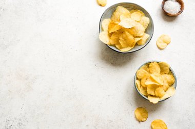Kâselerde ev yapımı patates cipsi. Beyaz arkaplanda çıtır patates cipsi, üst görünüm, kopyalama alanı.