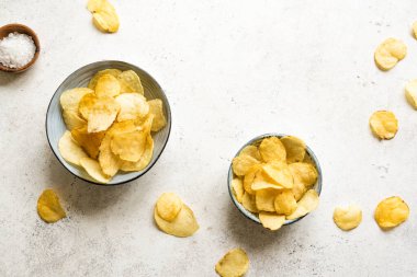 Kâselerde ev yapımı patates cipsi. Beyaz arkaplanda çıtır patates cipsi, üst görünüm, kopyalama alanı.