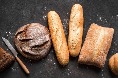 Siyah arkaplanda taze ekmek, üst görünüm, kopyalama alanı. Ev yapımı taze fırınlanmış çeşitli somun buğday ve çavdar ekmeği..