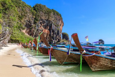 Uzun kuyruk teknesi ve turkuaz kristal berrak deniz suyu kireçtaşı uçurumu ve dağ Phra Nang Sahili, Krabi, Tayland