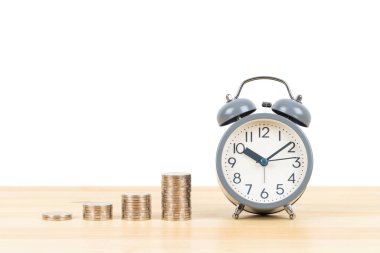 Para yığını ve alarm saati ahşap masa üzerinde beyaz zemin üzerinde, zaman kaydetme konsepti
