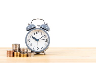 Para yığını ve alarm saati ahşap masa üzerinde beyaz zemin üzerinde, zaman kaydetme konsepti