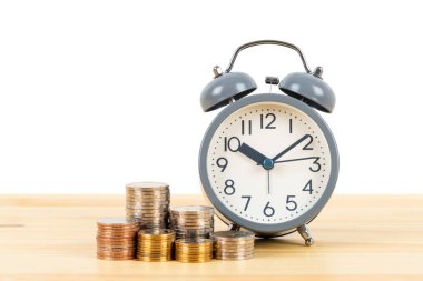 Para yığını ve alarm saati ahşap masa üzerinde beyaz zemin üzerinde, zaman kaydetme konsepti