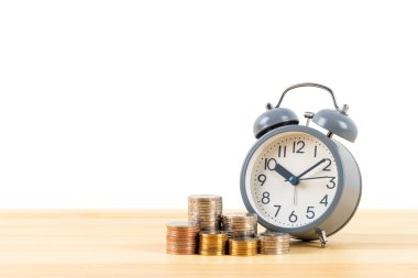 Para yığını ve alarm saati ahşap masa üzerinde beyaz zemin üzerinde, zaman kaydetme konsepti