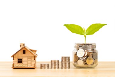 Bozuk para kavanozu ve deste, ve ahşap masa üzerinde model ev beyaz arka plan, ipotek konsepti