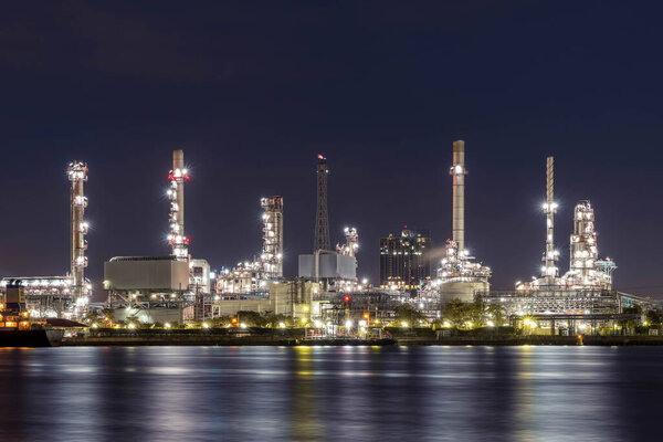 Oil refinery at night petrochemical and energy industry with refection on river