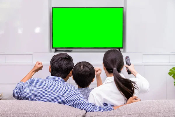 Mutlu Asyalı ailenin evdeki oturma odasında birlikte televizyon izlemesi; neşeli ve sinemayla eğlenceli, yeşil ekranlı