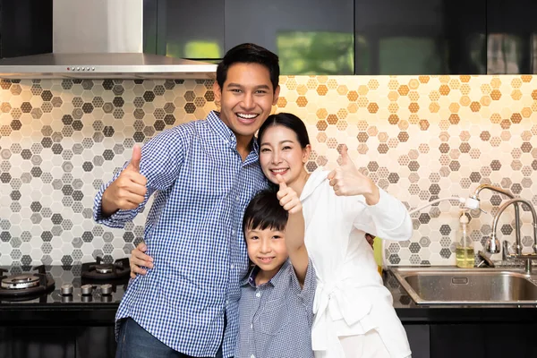 美しいです若いですアジアの女性母とともに男の夫と若いです男の子の家族で現代的なキッチンルーム カメラを見て 親指アップ — ストック写真