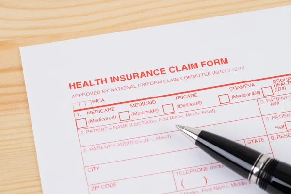 Health insurance claim form with pen on wooden desk