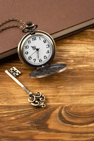 Ahşap Arka Planda Anahtarı Kitabı Olan Klasik Bir Cep Saati — Stok fotoğraf