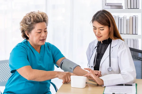 Aziatische Vrouwelijke Arts Meten Van Bloeddruk Senior Oudere Patiënt Kijken — Stockfoto