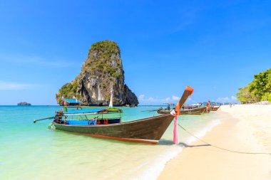 Uzun kuyruk teknesi ve turkuaz kristal berrak deniz suyu kireçtaşı uçurumu ve dağ Phra Nang Sahili, Krabi, Tayland