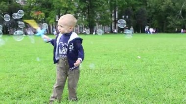 Küçük çocuk sabun köpüğüyle oynuyor.