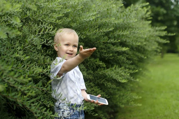 Маленький хлопчик з телефоном влітку в парку — стокове фото