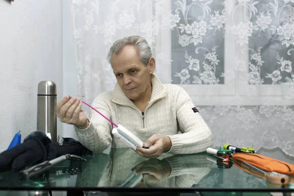 Älterer Mann checkt vor dem Winterangeln die Ausrüstung lizenzfreie Stockfotos