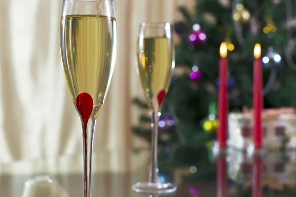 Weinglas mit Champagner, Weihnachtsbaum, Geschenken und Kerzen Stockfoto