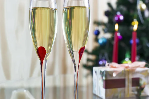 Zwei Weingläser mit Champagner, Weihnachtsbaum, Geschenken und Kerze Stockbild