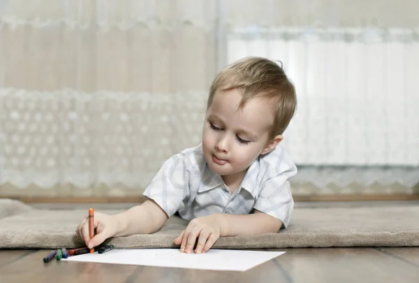Kleiner Junge zeichnet mit Buntstiften, die auf dem Boden liegen — Stockfoto