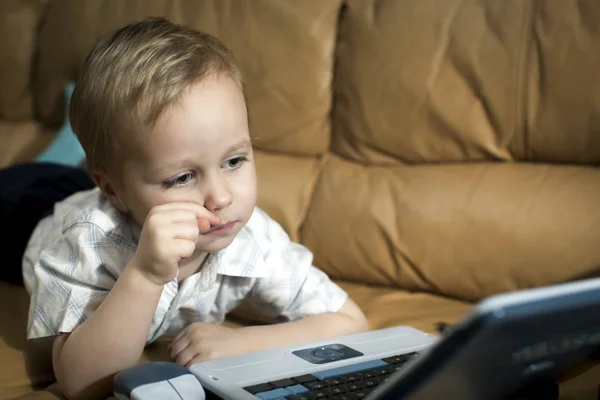 Menino está brincando no computador de ensino em casa no co — Fotografia de Stock