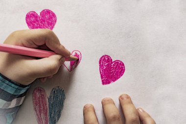  Çocuğun sevgisini ifade eden kırmızı bir kalp, çocuğun elleri, çizim defteri ve kalem / kalem. Çocuk, Babalar Günü, Sevgililer Günü ya da Anneler Günü için kalp çiziyor..