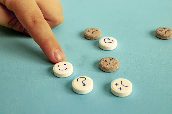 Gülen suratlı haplar. Antidepresan ve iyileşme konsepti. Çocuk hap alıyor, elinde beyaz bir tablet tutuyor. İlaç, antidepresan veya vitamin kavramı