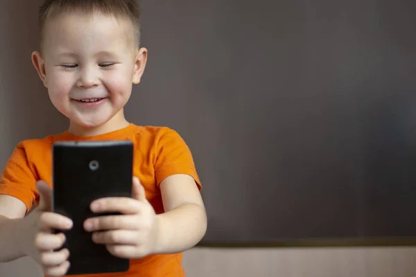 Egy Fiú Telefonnal Aranyos Kisfiú Játszik Okostelefonnal Egy Kisfiú Narancssárga — Stock Fotó