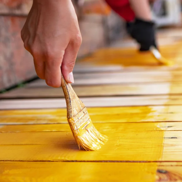 close up in gloves painting a wood wall in the yellow. Renovation.