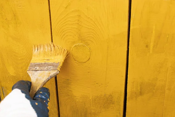 close up in gloves painting a wood wall in the yellow. Renovation.