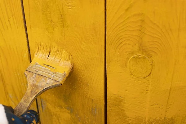 close up in gloves painting a wood wall in the yellow. Renovation.