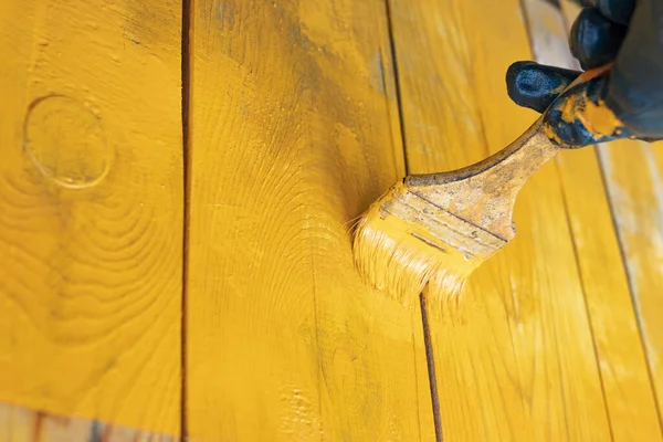 close up in gloves painting a wood wall in the yellow. Renovation. creative design house renovation theme. How to Paint Wooden Surface. Selected focus